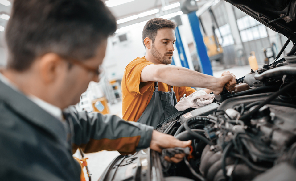 Technicians working under the hood inside the Harris Cars collision repair shop