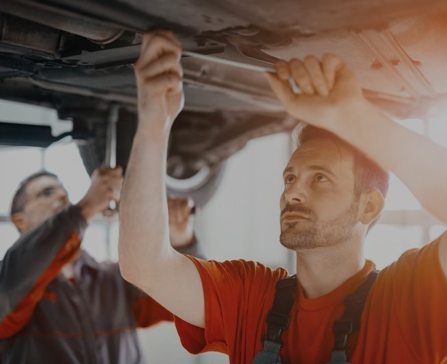 Technician performing inspection work underneath a vehicle