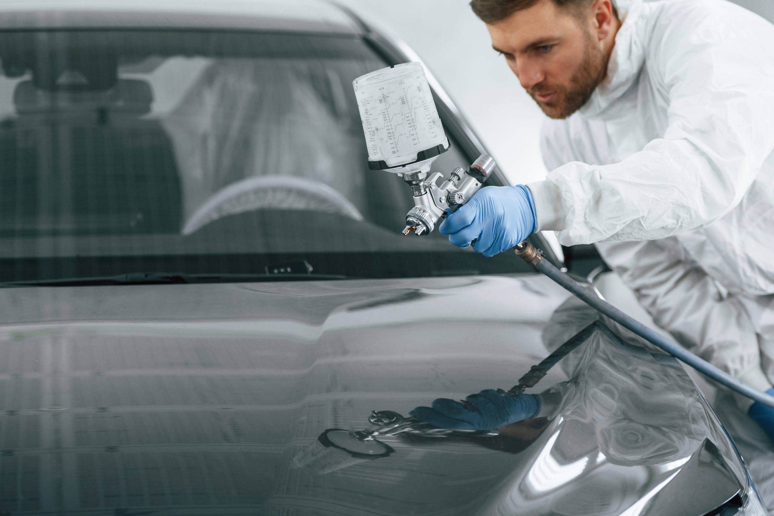Technician spray painting a vehicle in a collision repair booth
